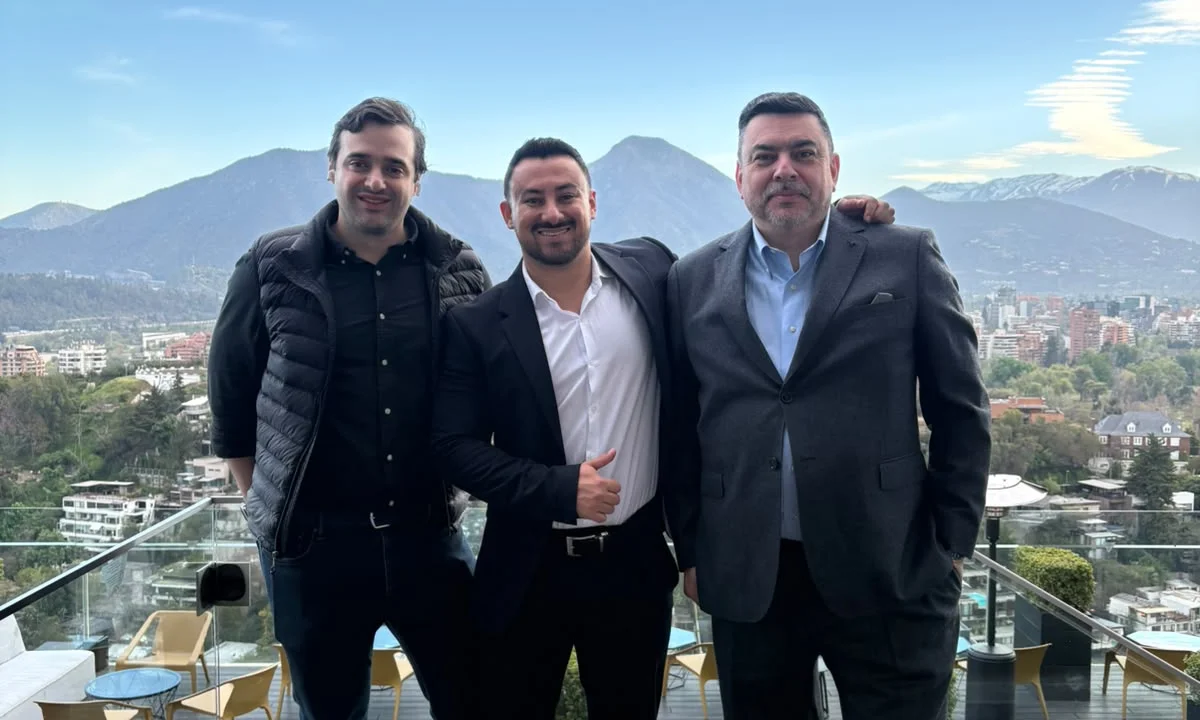 Tres colaboradores de GFT Technologies Chile del evento con la ciudad y las montañas de Santiago de Chile al fondo.