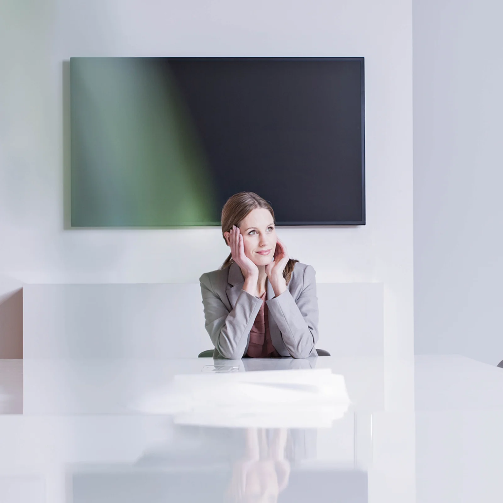 Vision and Innovation in the Modern Workplace Business professional sitting at a modern conference table, looking thoughtful and inspired in a bright minimalist office setting.
