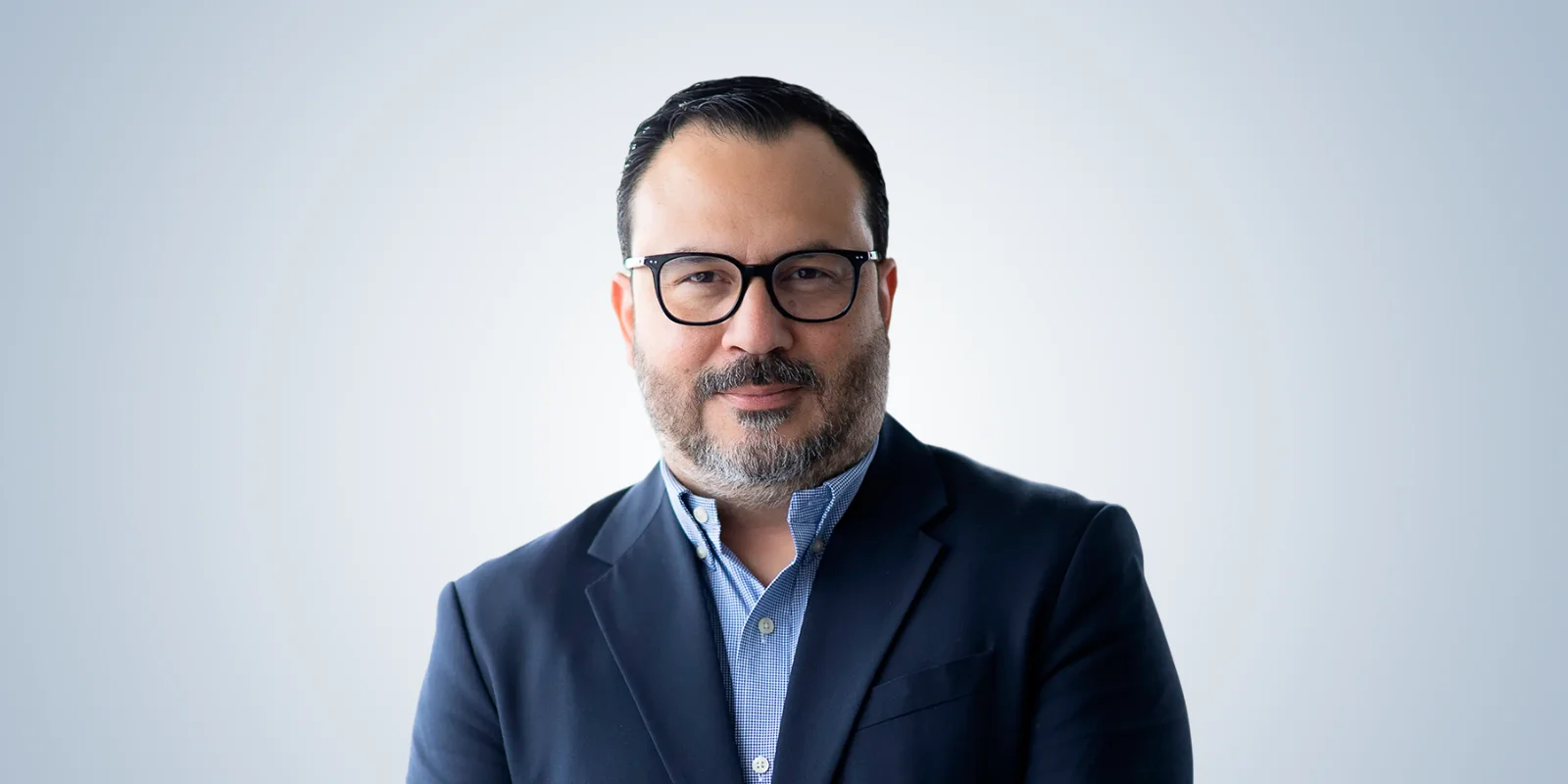 Portrait of Fabián Salaza in a blue checkered suit and glasses.