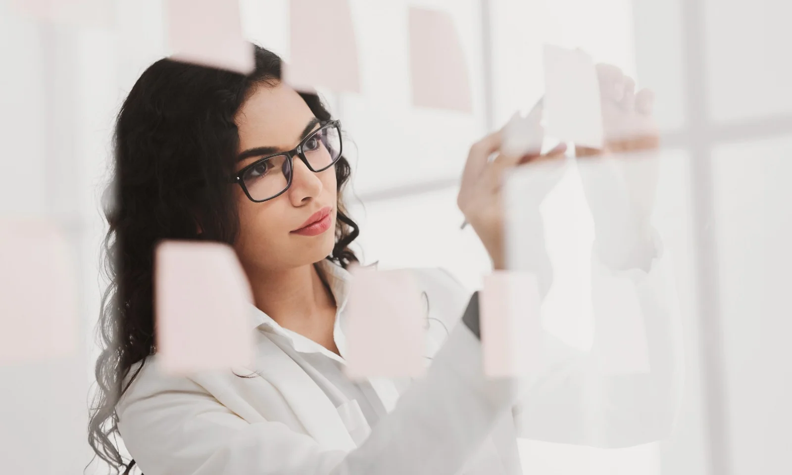 Preparing for AI-led insurance decisions Insurance professional organizing notes on a glass wall while planning AI adoption and decision-making.