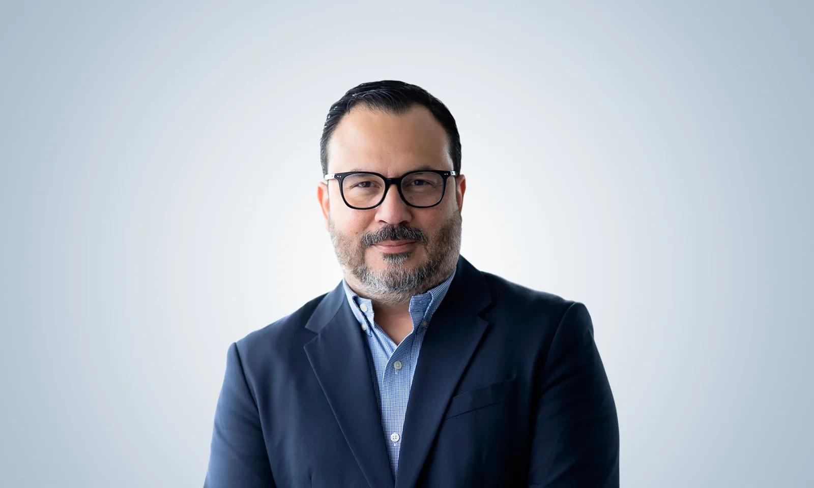 Retrato de Fabián Salaza con traje de cuadros azules y gafas.