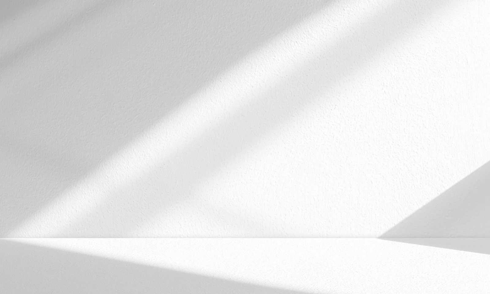 Minimalist White Wall with Geometric Light and Shadows White textured wall illuminated by diagonal light beams, creating abstract geometric shadow patterns in a minimalist composition.