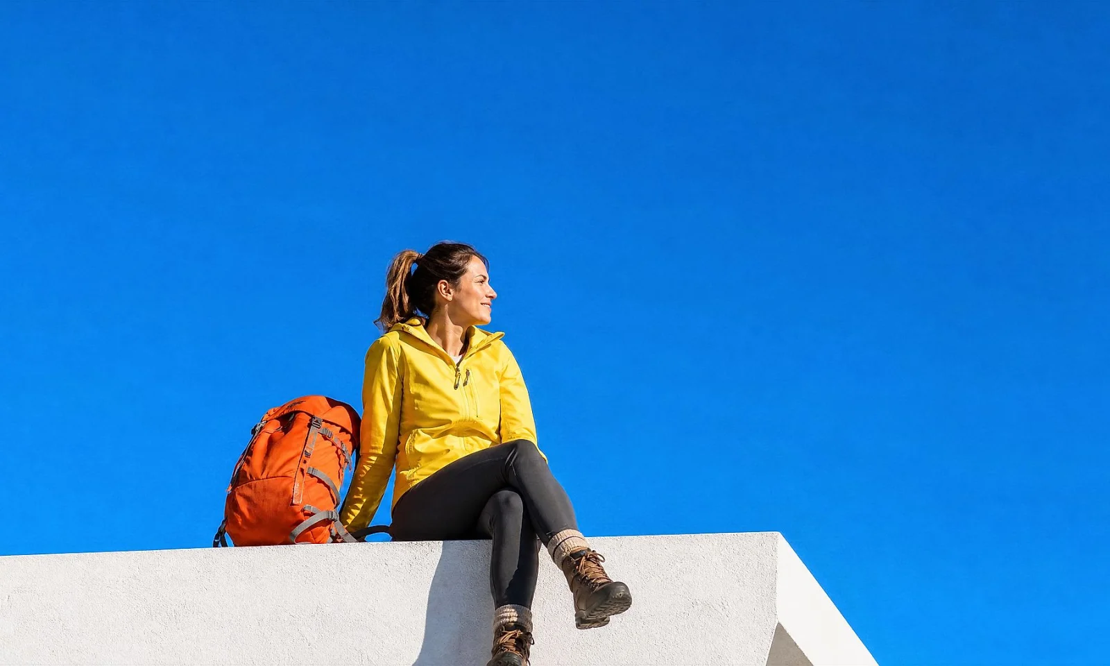 Femmes assises sur un toit avec un sac à dos orange. Femmes assises sur un toit avec un sac à dos orange.
