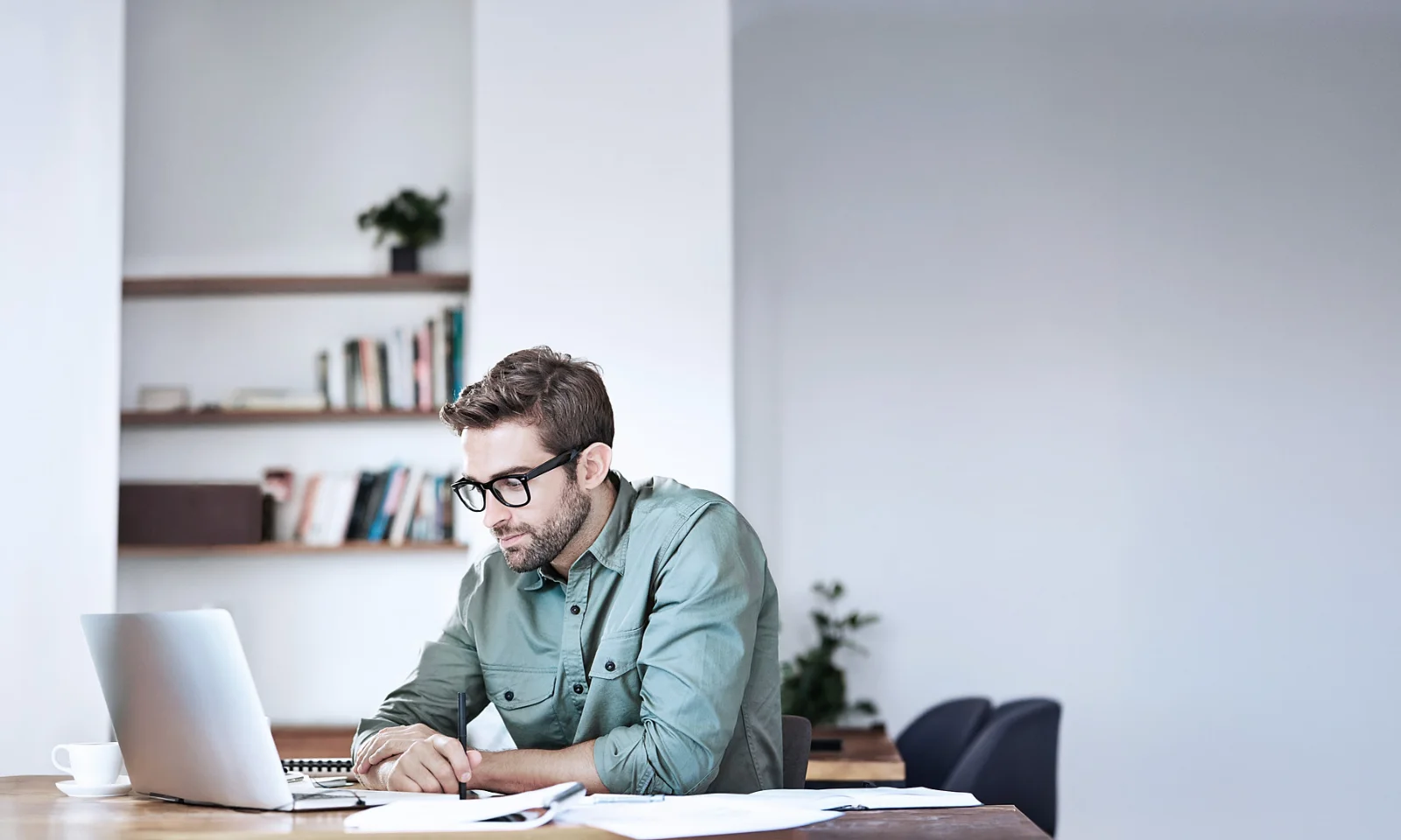 GFT Blog - Ingeniería de plataformas, agentes inteligentes e IA generativa: el nuevo ecosistema del desarrollo tecnológico Group of business professionals standing together in a bright, open, minimalist concrete space, collaborating and reviewing documents under natural light.