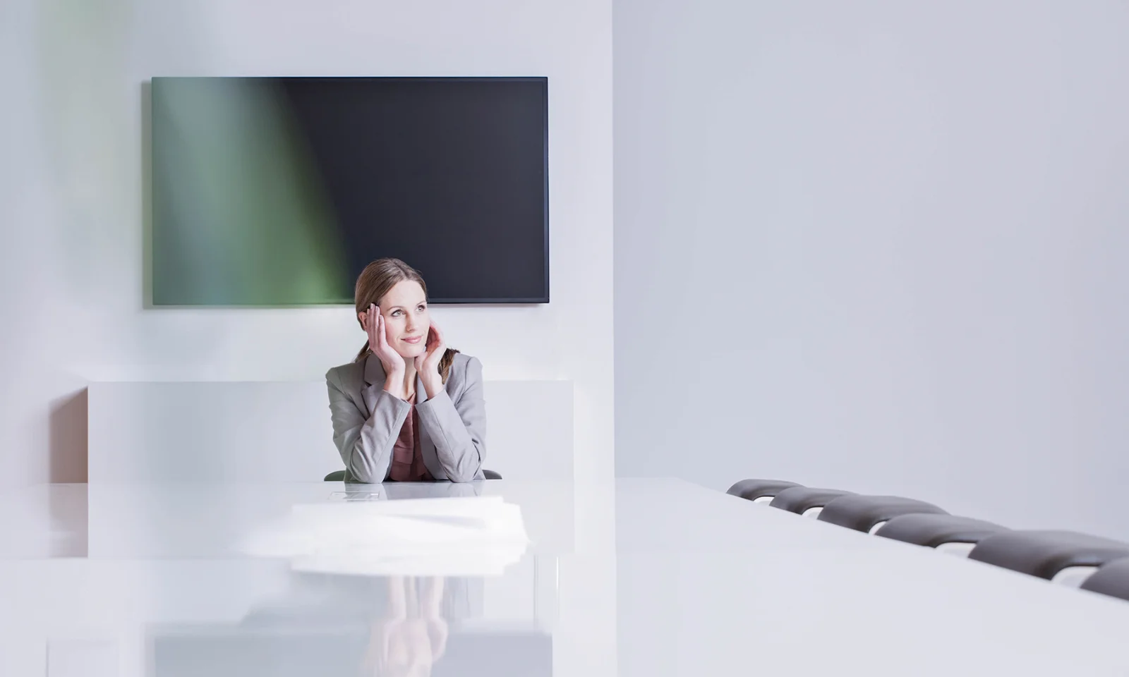 Business professional sitting in a modern conference room, reflecting on ideas and strategies for innovation and growth.