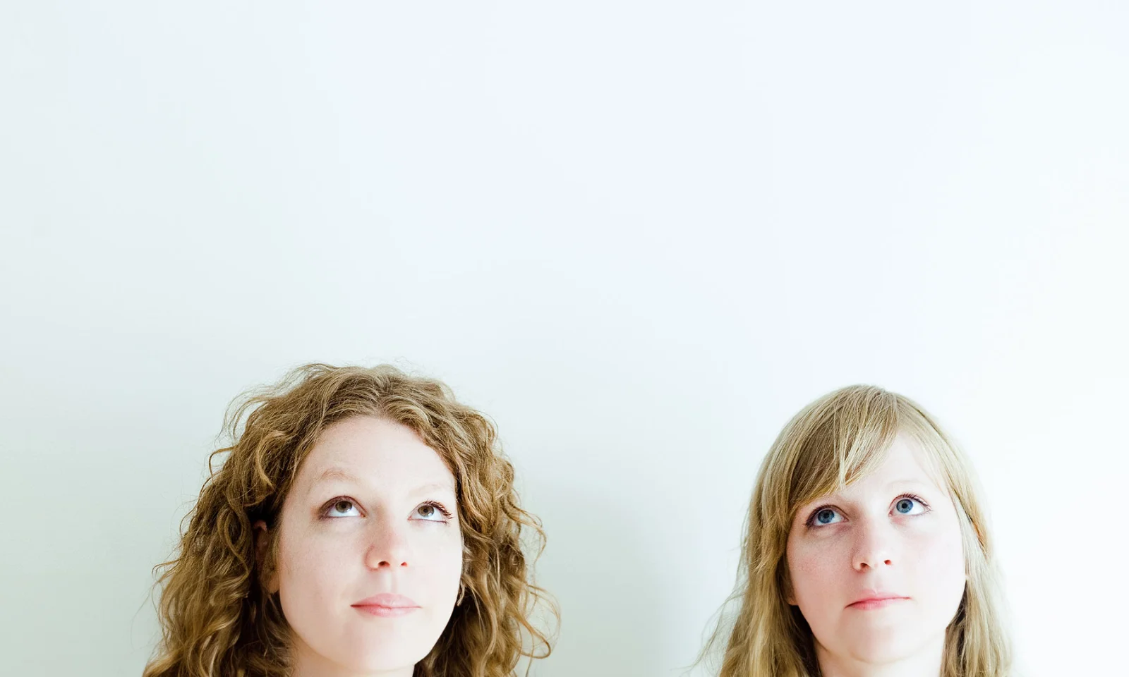 GFT Blog: Hitos Destacados 2024 Two people looking upward with thoughtful expressions against a light background, symbolizing curiosity, imagination, and innovation.