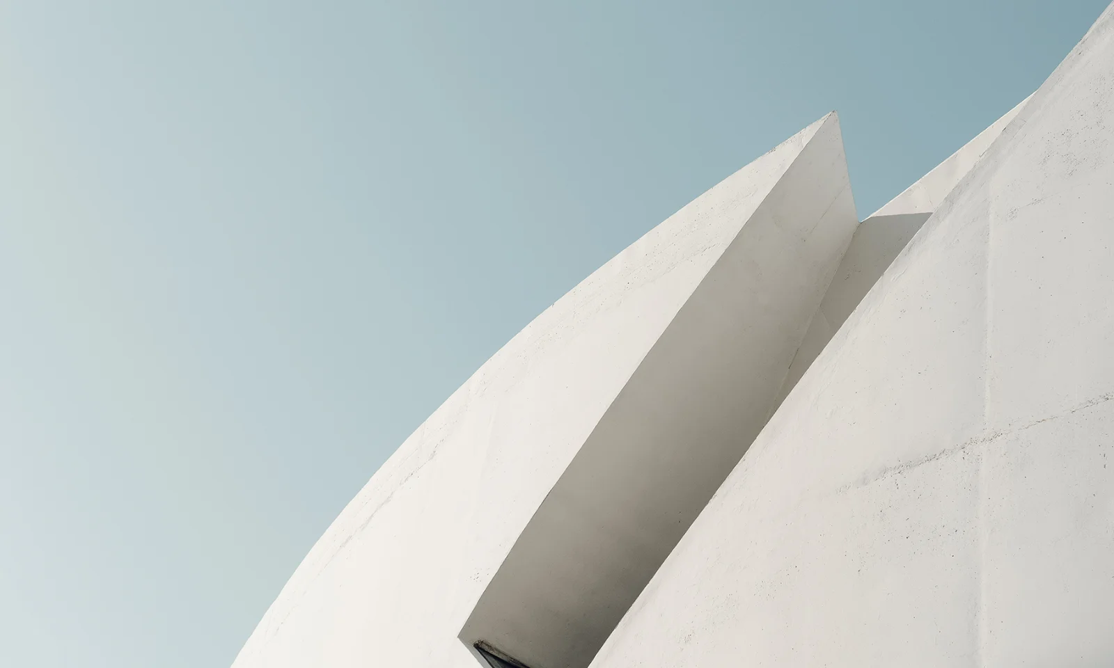 GFT Blog - Group Insurance in Canada Minimalist white concrete structure with sharp geometric lines against a clear blue sky, symbolizing innovation and structural clarity.