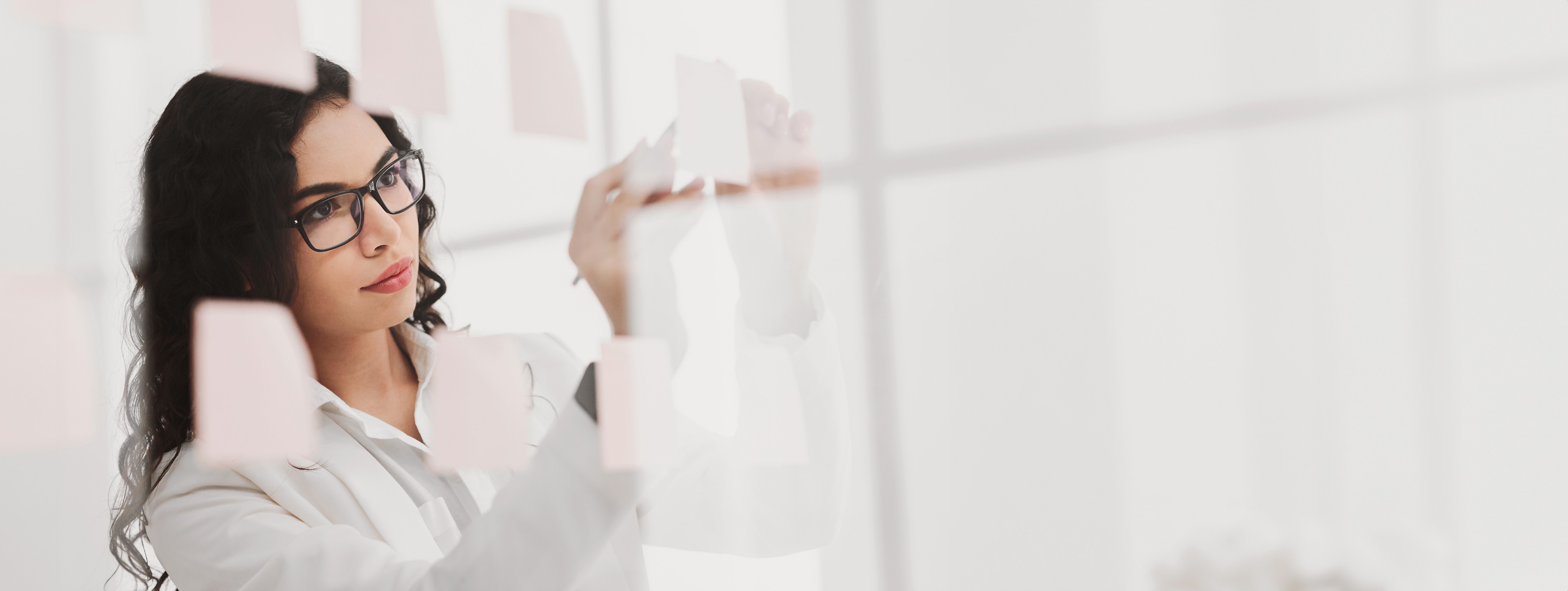 Insurance professional organizing notes on a glass wall while planning AI adoption and decision-making.