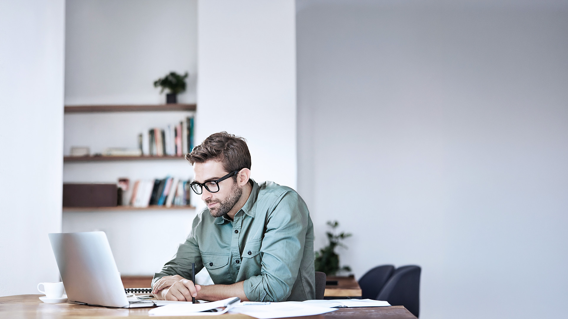 Group of business professionals standing together in a bright, open, minimalist concrete space, collaborating and reviewing documents under natural light.