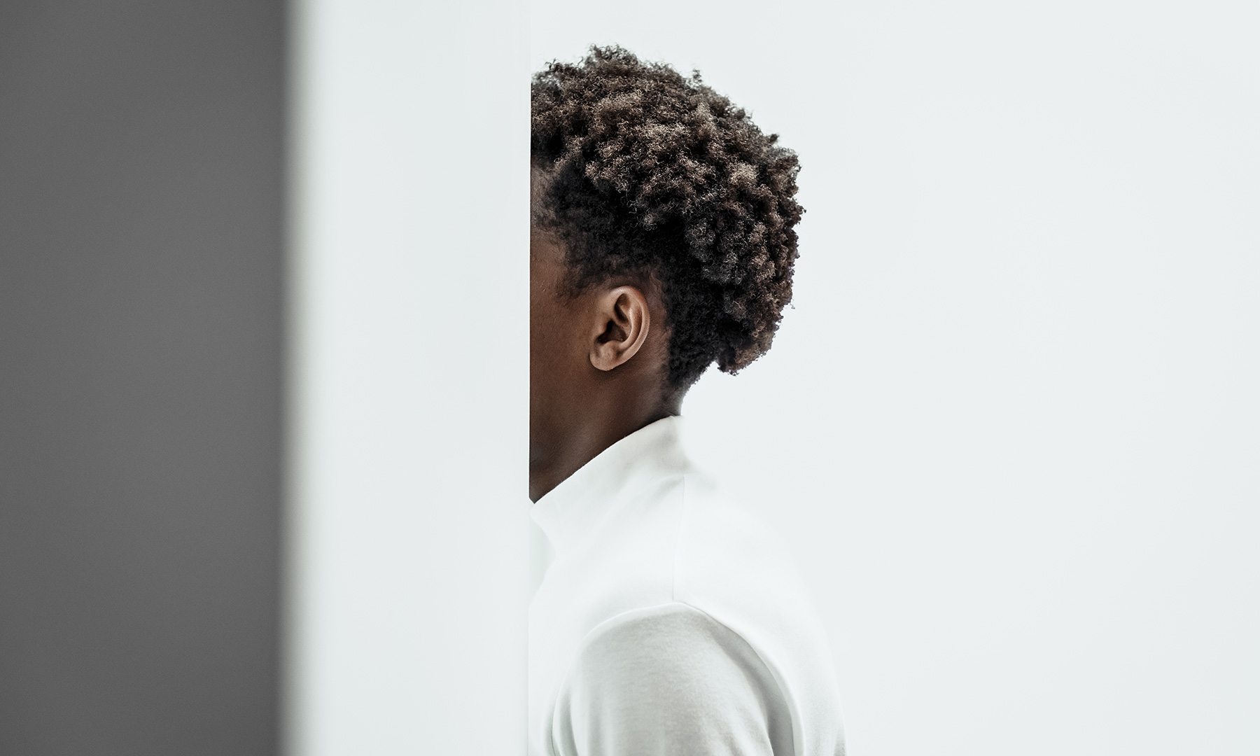 Portrait of Person in Minimalist Environment Close-up of a person standing beside a wall in a minimalist, modern setting, symbolizing focus, individuality, and innovation.
