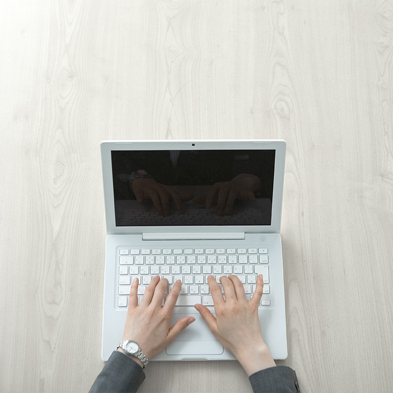 AI and Machine Learning Hands typing on a white laptop on a light wooden desk, symbolizing digital collaboration and innovation